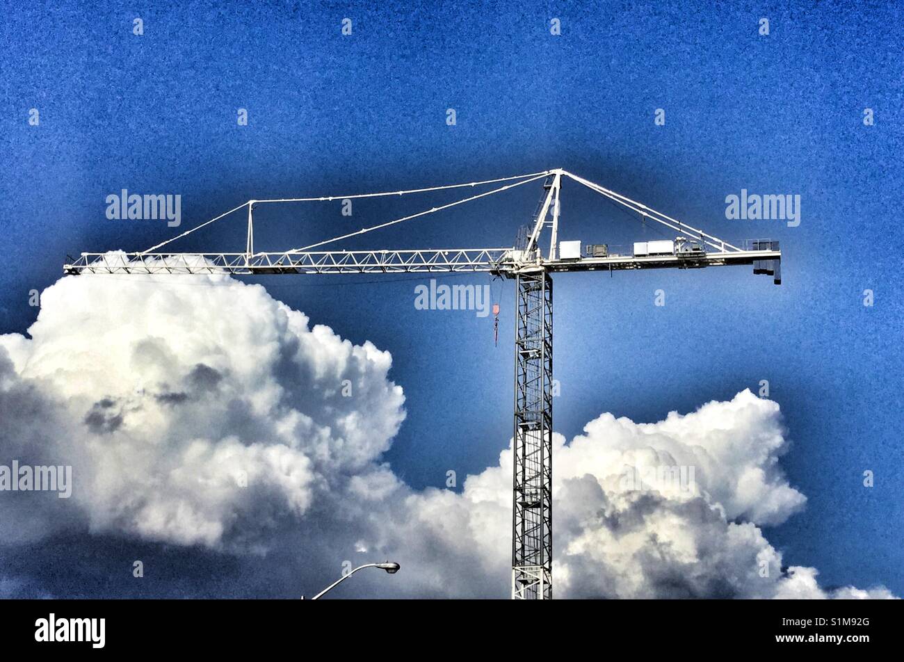 Grue de construction s'élevant au-dessus des nuages. Banque D'Images