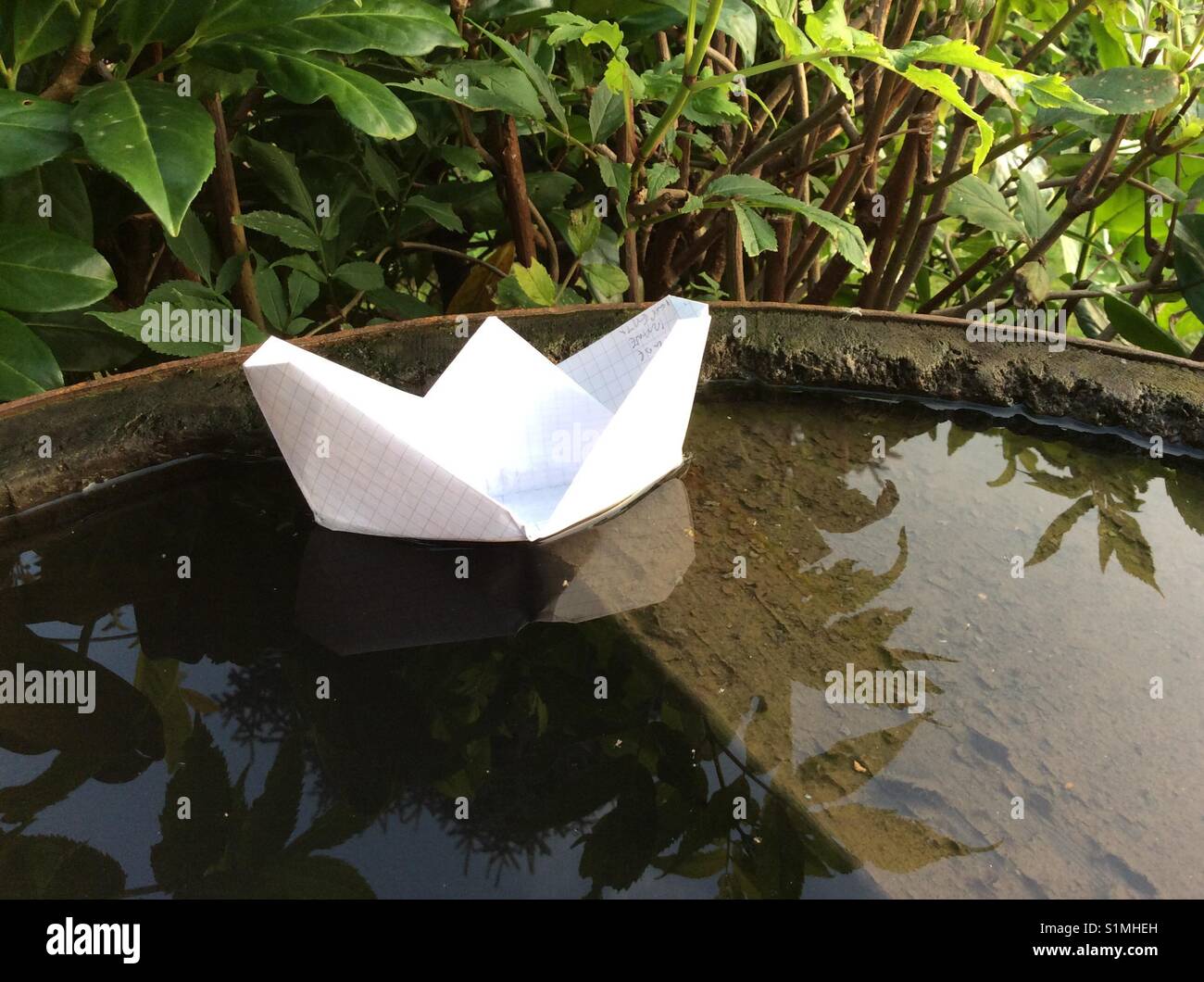Bateau de papier flottant sur l'eau de pluie tonneau de vin de cru Banque D'Images