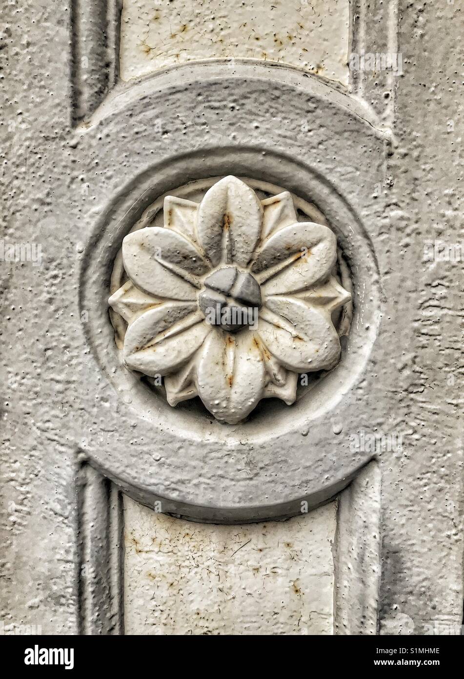 Détail architectural de fleurs sculptées dans la pierre. Texture rugueuse et symétrie. Banque D'Images