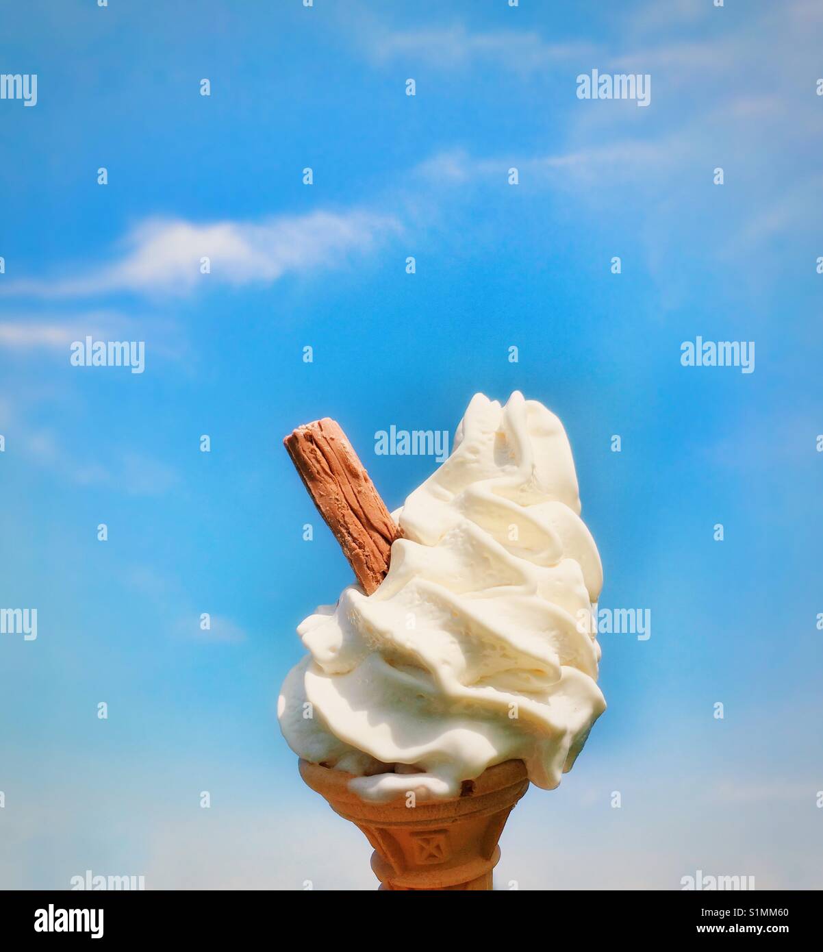 Cornet de crème glacée avec de la crème glacée et le chocolat flake against a blue sky Banque D'Images
