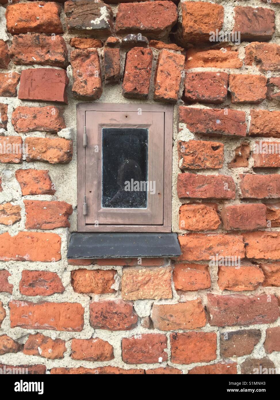Petite fenêtre dans mur de briques Banque D'Images