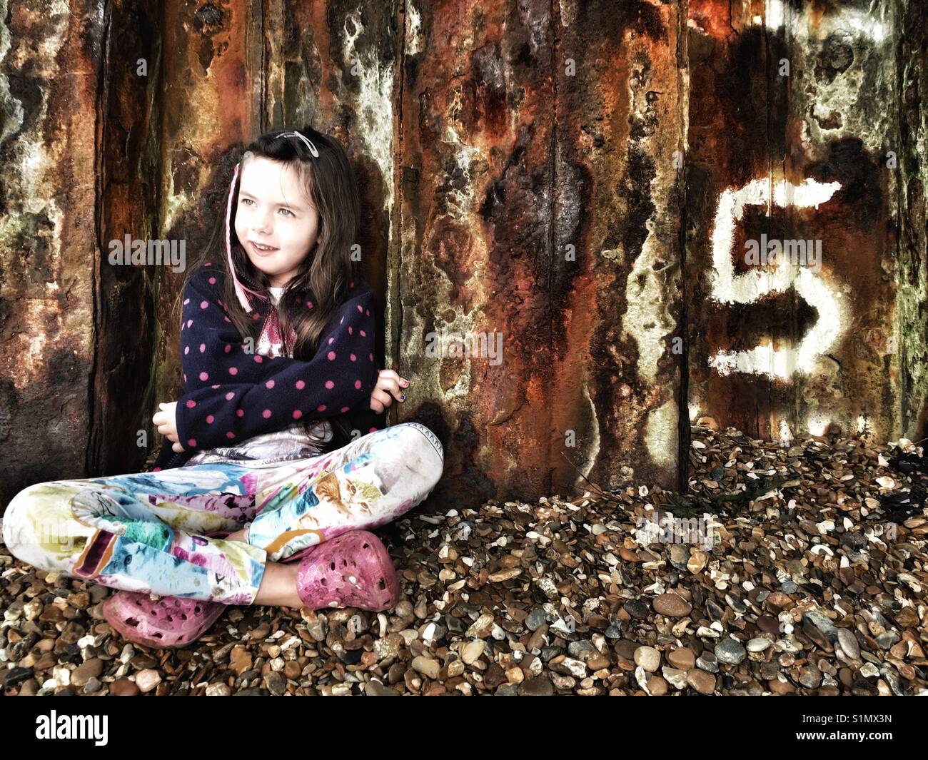 5 ans, assis à côté de la digue, Ferry Bawdsey, Suffolk, Angleterre. Banque D'Images