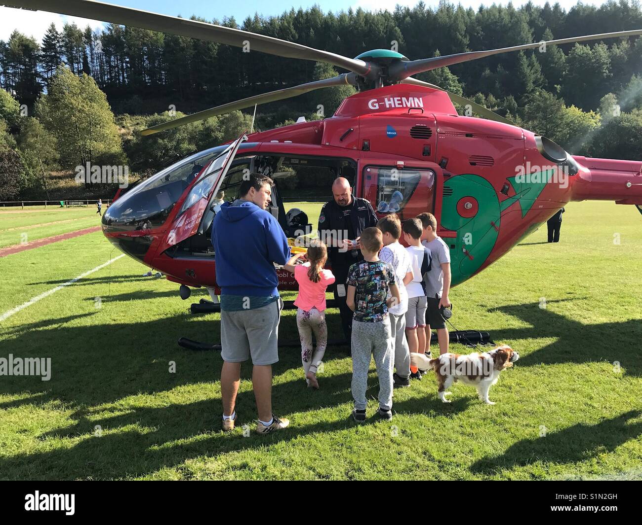 Le pilote d'un pays de Galles Air Ambulance parle aux enfants après l'atterrissage sur un terrain de sport Banque D'Images