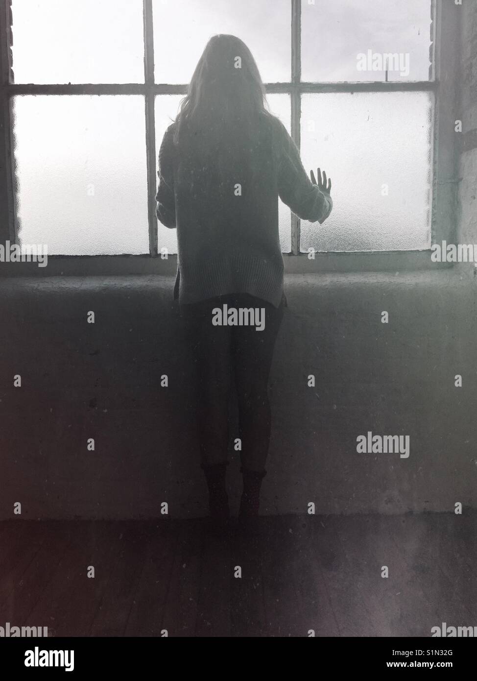 Vue arrière silhouette d'une femme debout près de la fenêtre Banque D'Images