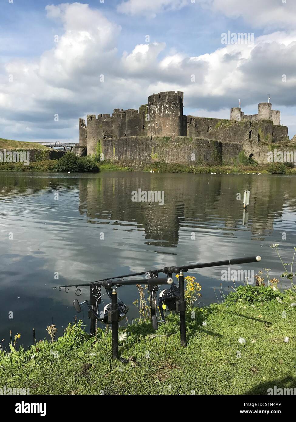 Un pêcheur à la canne à pêche sur la banque des douves du château de Caerphilly - Image de stock capturée avec un smartphone