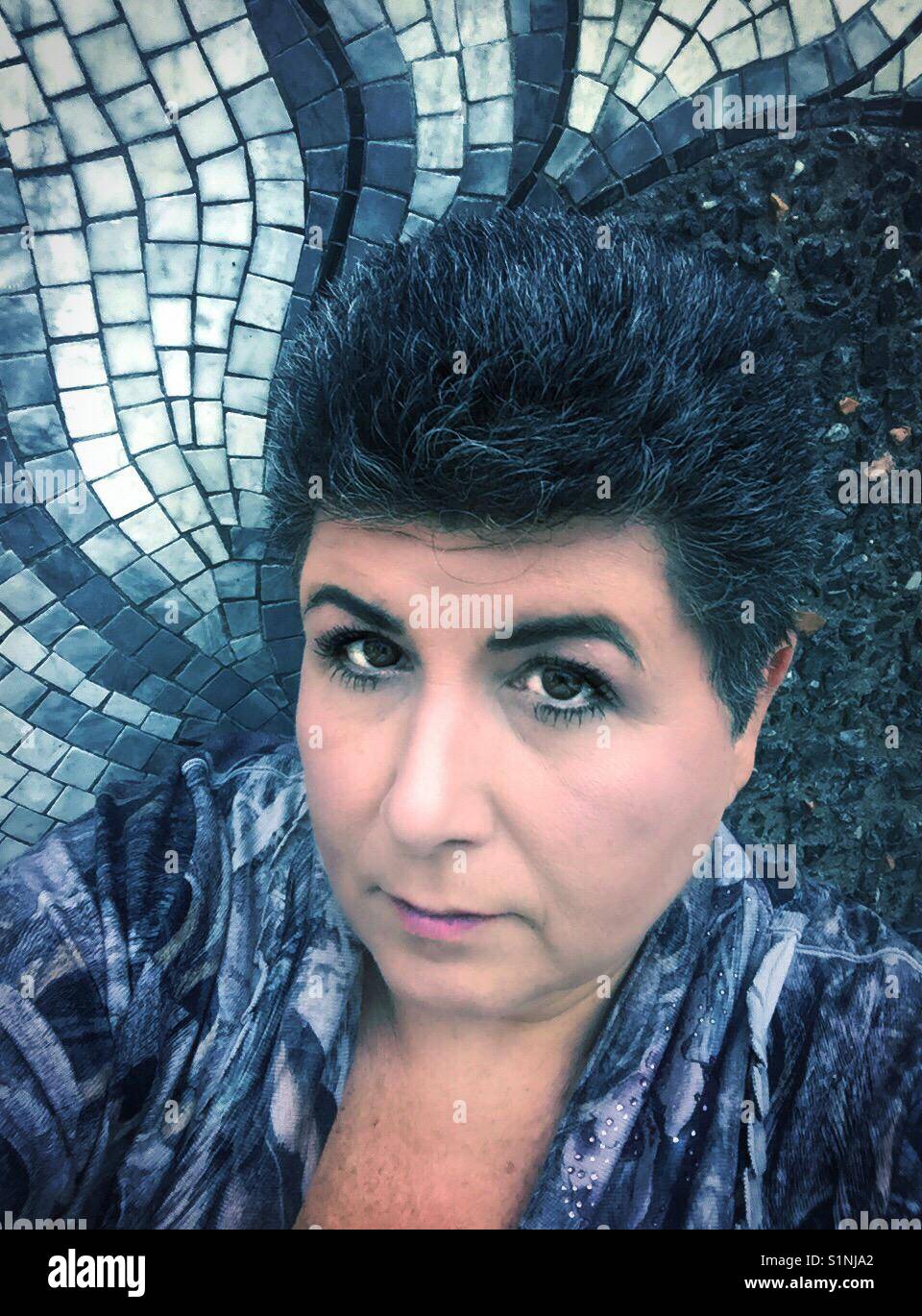 Un portrait colo d'une femme d'âge moyen de race blanche avec des cheveux foncés avec des gris dedans. Banque D'Images