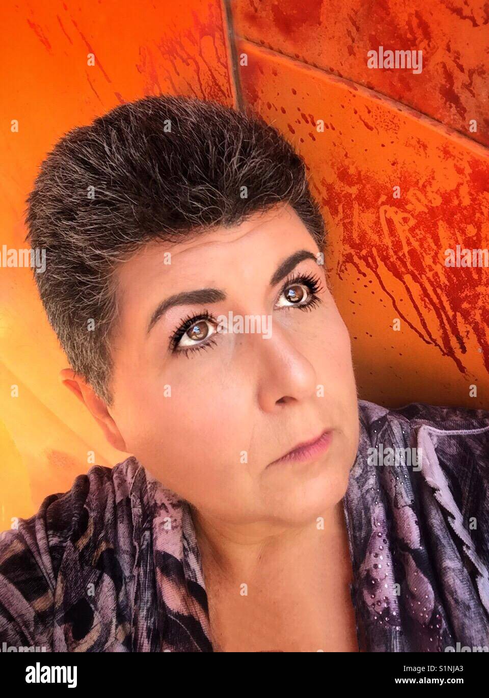 Un portrait colo d'une femme d'âge moyen de race blanche avec des cheveux foncés avec des gris dedans. Banque D'Images