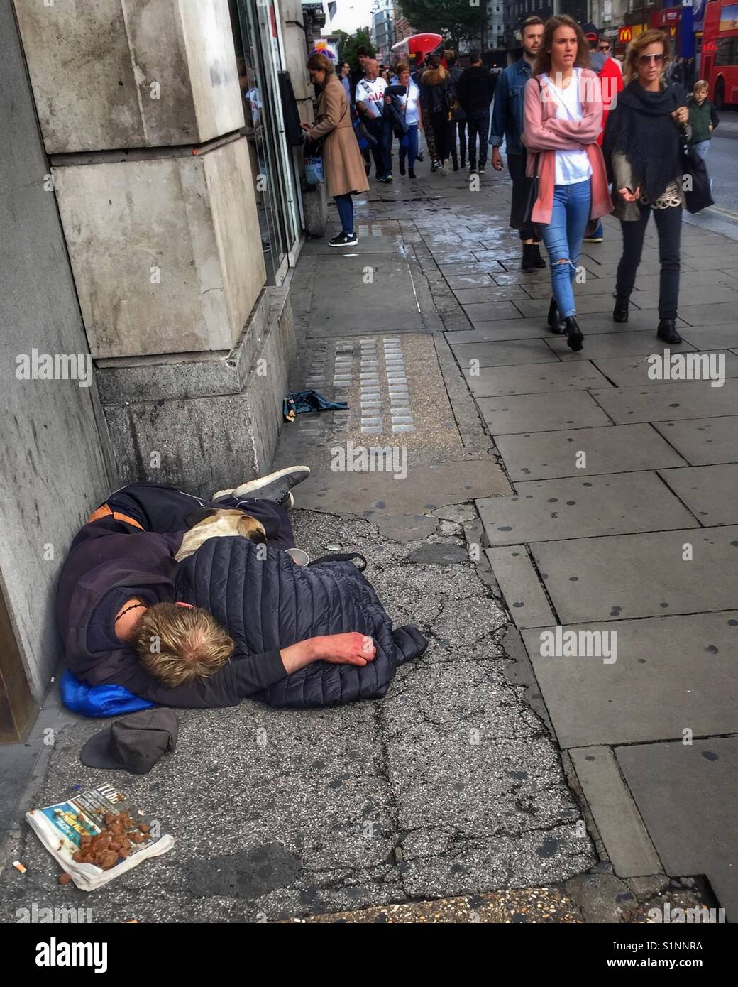 Un sans-abri dort avec son chien à l'extérieur d'un magasin sur Tottenham Court Road à Londres, Angleterre Banque D'Images