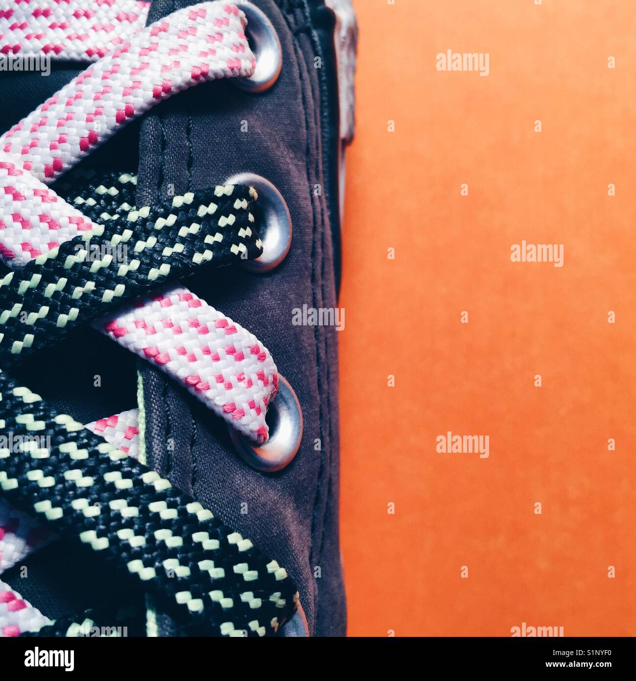 Un close up detail shot d'une femme avec des lacets de chaussures de funky sur fond orange Banque D'Images