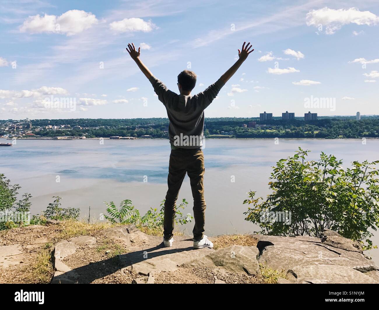 Un homme avec les bras tendus, debout sur le new jersey palisades donnant sur l'Hudson et à new york. Banque D'Images