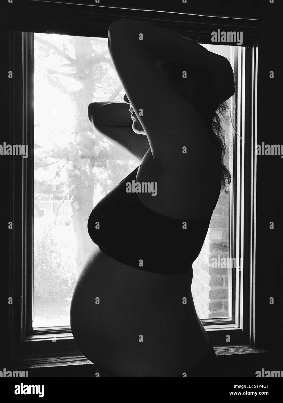 Une femme enceinte debout près d'une fenêtre. Banque D'Images
