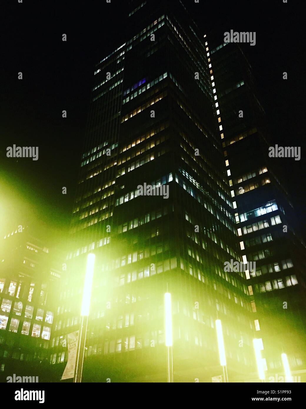 Feux de brume verte éclatante en face d'un immeuble de bureaux dans la nuit. - Image de stock capturée avec un smartphone