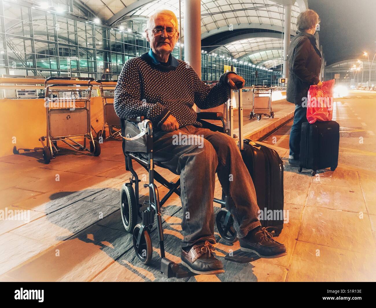 Hauts homme et une femme en attente de la navette de l'aéroport la nuit. El Altet Aéroport, Alicante, Espagne. Banque D'Images