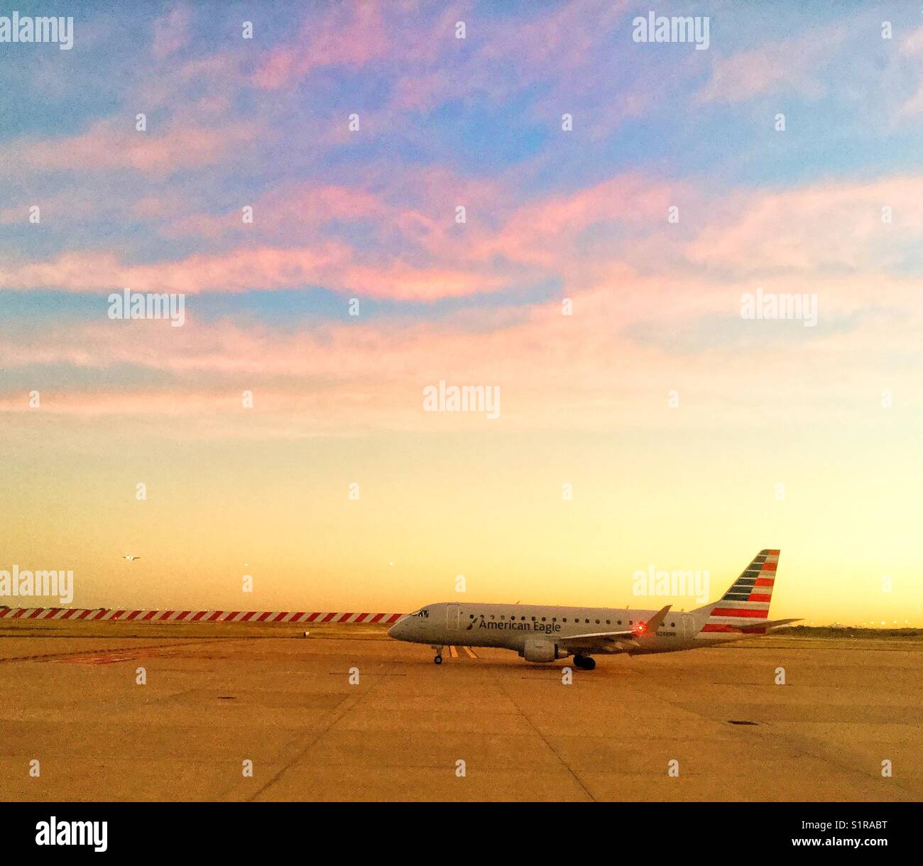 Un avion d'American Airlines sur la piste, prêt à décoller au coucher du soleil. Banque D'Images