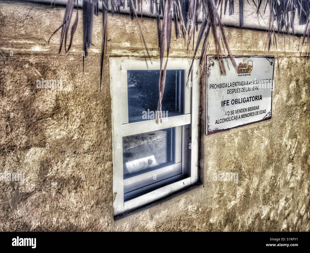 Un panneau d'avertissement en espagnol posté à côté d'une très petite fenêtre de ticket de stand un bar de San José del Cabo. Banque D'Images
