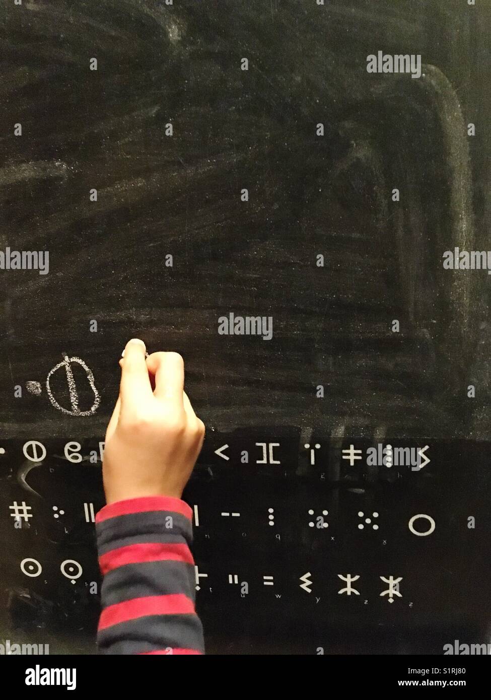 Un garçon écrit en tifinagh sur un tableau noir Banque D'Images