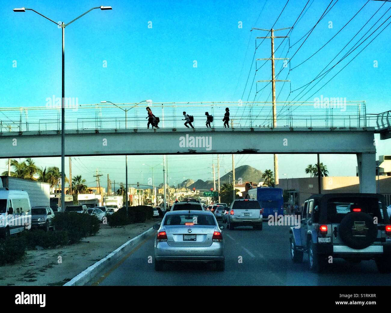 Les enfants de l'école tournant sur un pont, sur une rue animée de Cabo San Lucas, Mexique. - Image de stock capturée avec un smartphone
