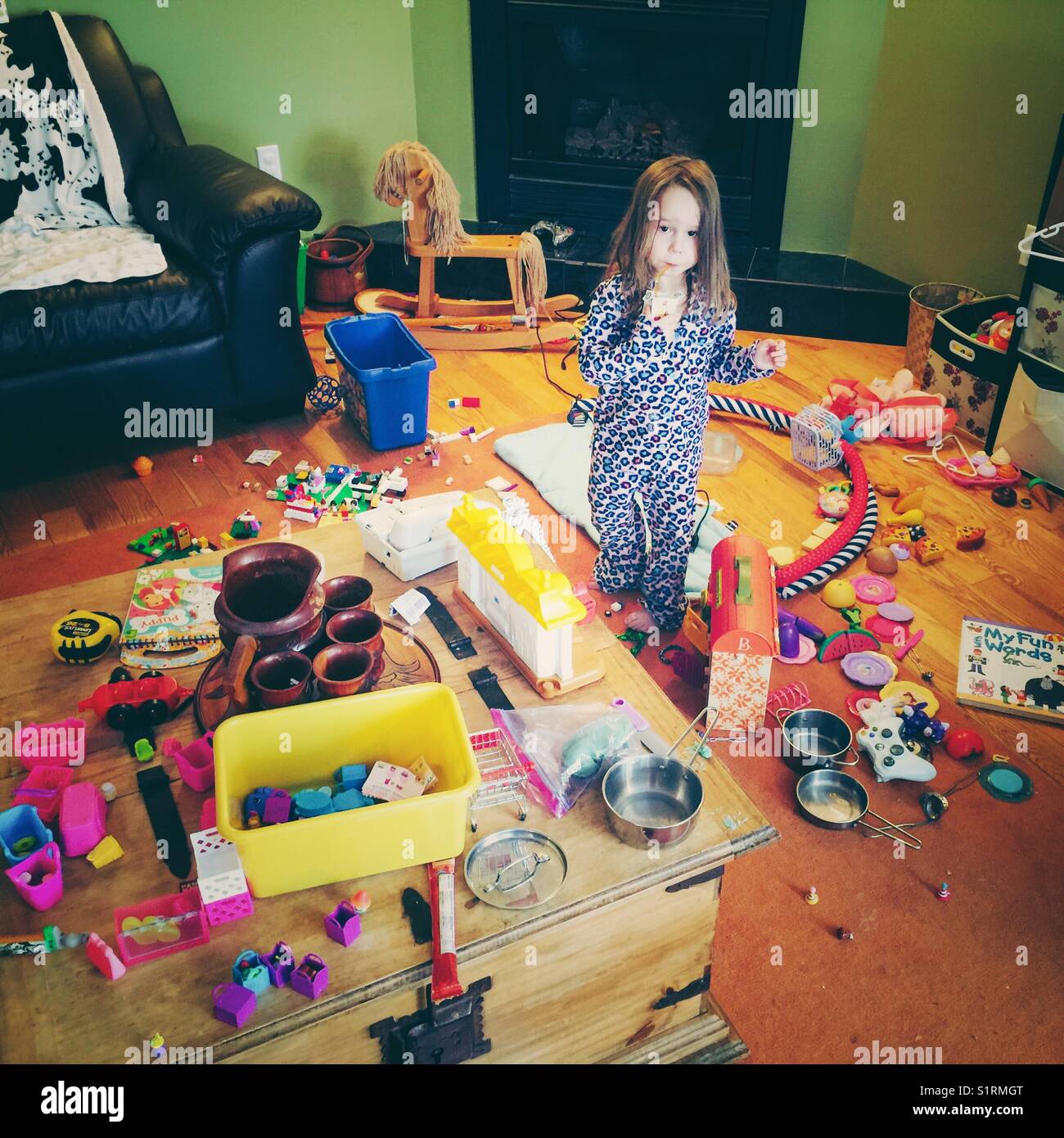 Jeune fille innocente à au milieu de l'énorme gâchis de jouets qu'elle a fait Banque D'Images