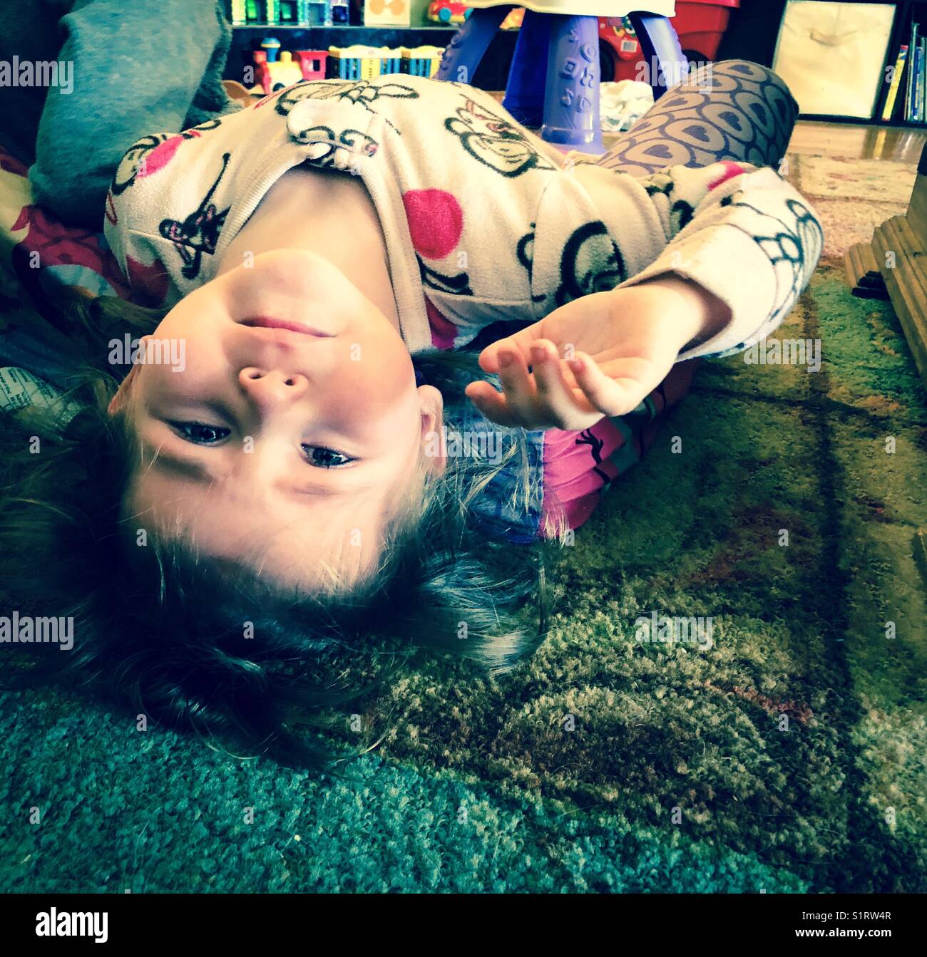 Petite fille posée sur le sol, regardant à l'envers à l'appareil photo avec des yeux teary Banque D'Images