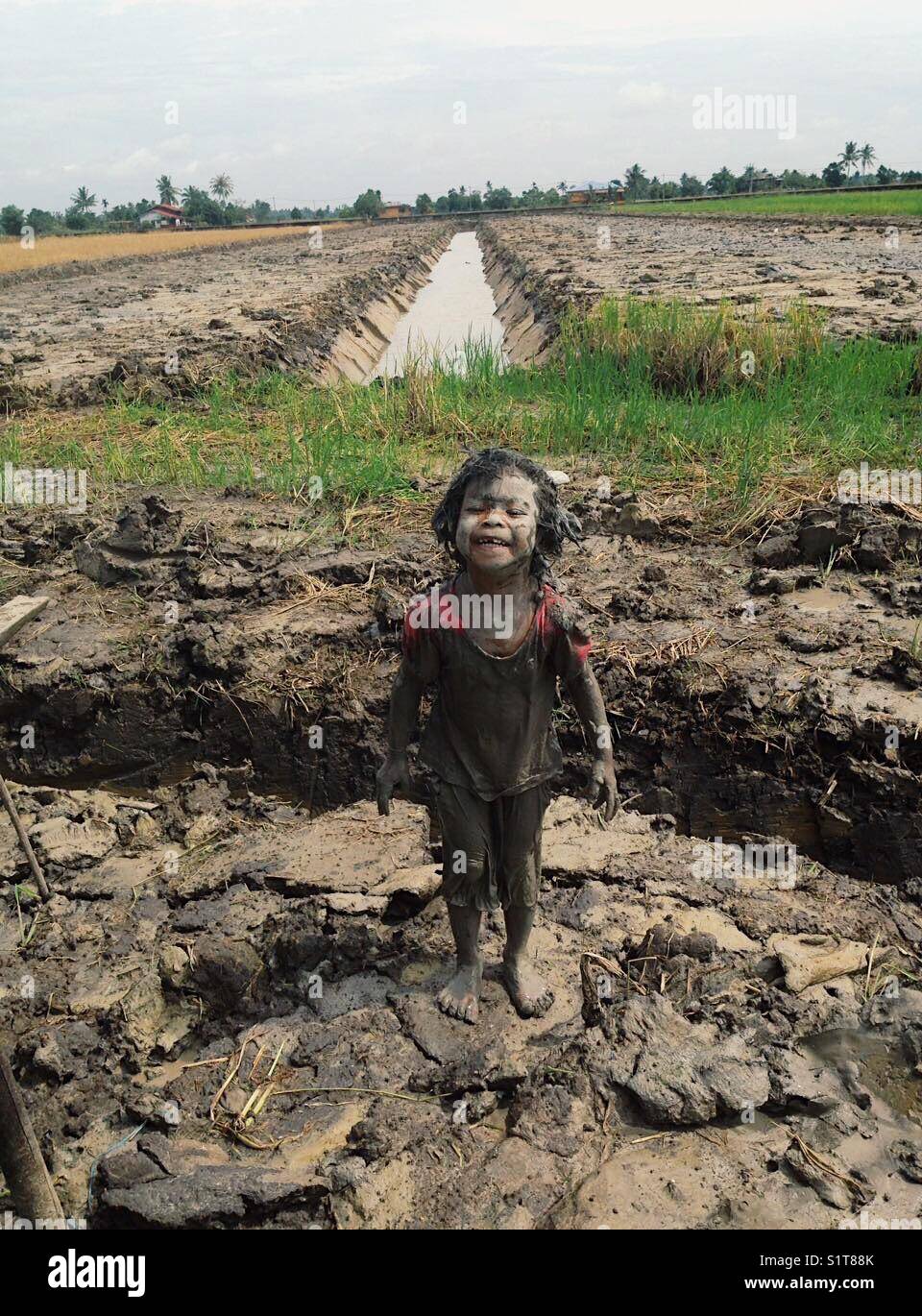 Fille dans la boue par la rizière Banque D'Images