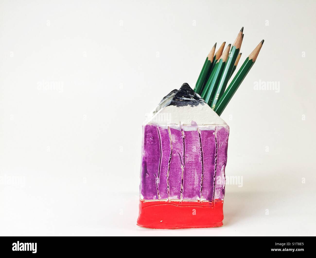 En forme de crayon crayons dans récipient en céramique sur fond blanc Banque D'Images