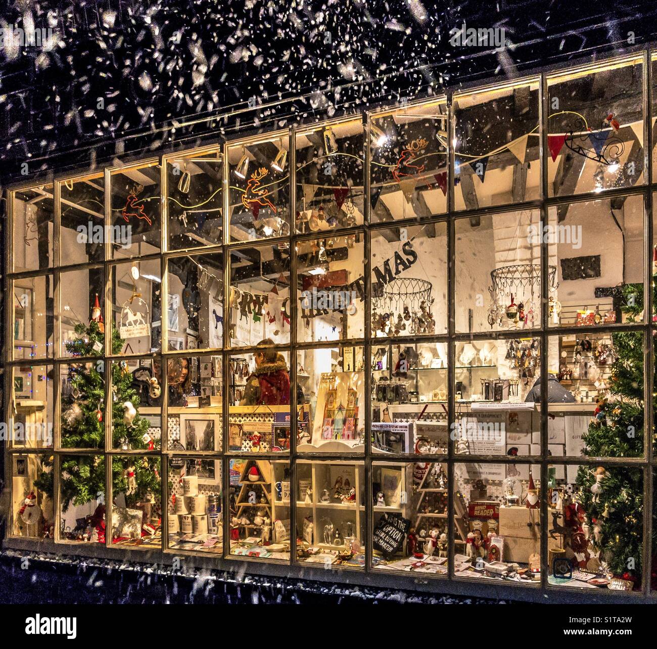 Fenêtre d'une boutique de cadeaux à Noël avec la neige qui tombe à l'extérieur Banque D'Images