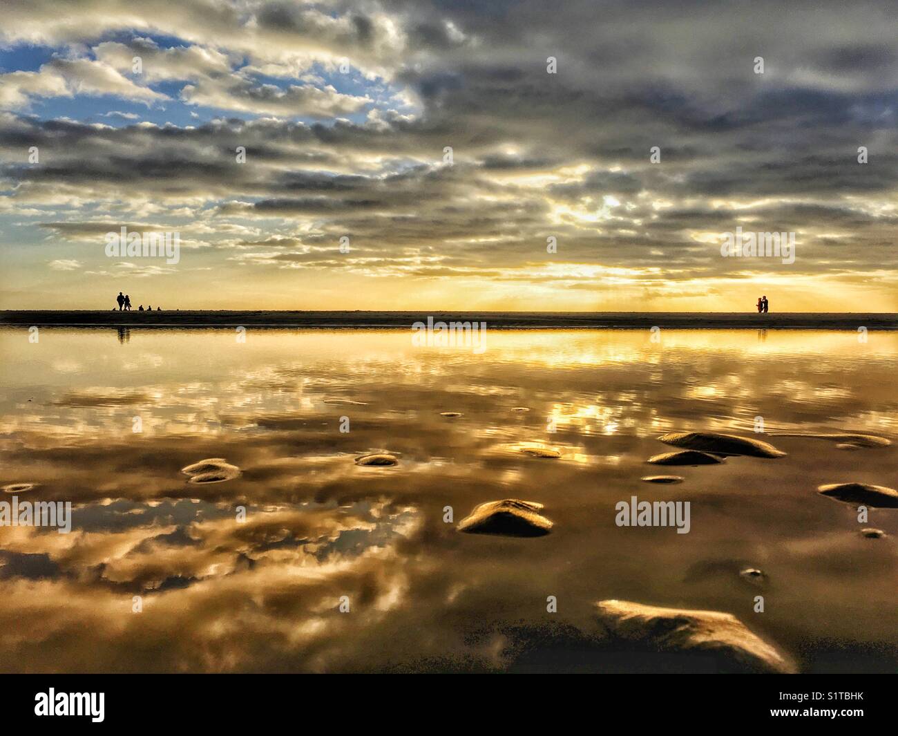 Sky reflète dans n extérieure à marée basse sur la plage de Blackpool avec des gens qui marchent sur l'horizon Banque D'Images
