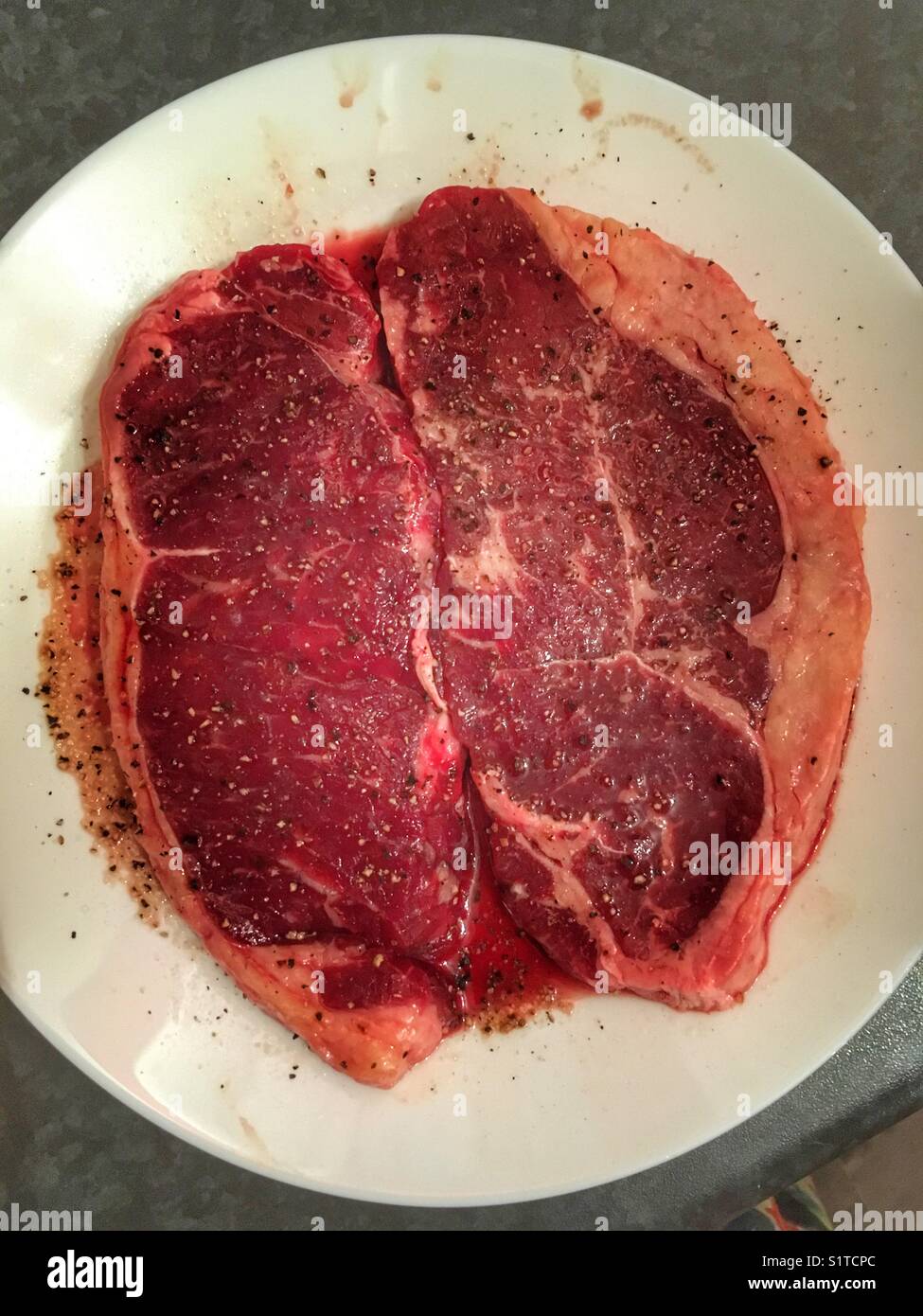 Deux steaks de surlonge de wagyu étant assaisonné avant la cuisson. Banque D'Images