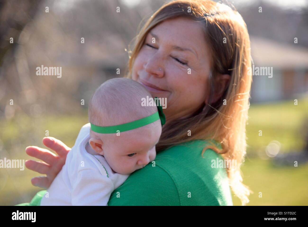 Femme tenant bébé dehors le jour de la St Patrick Banque D'Images