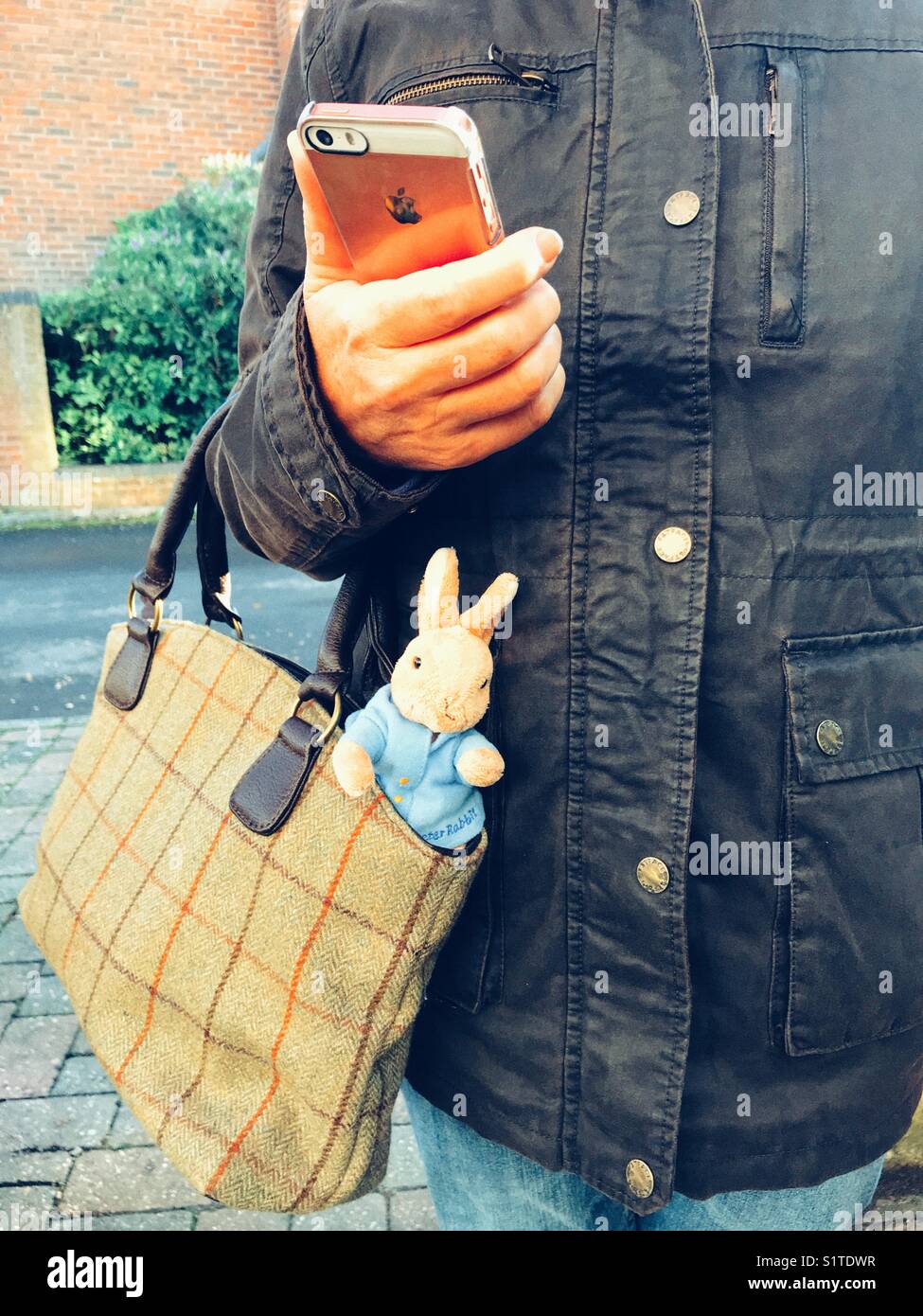 Mère au travail, à l'aide de téléphone mobile et avec un jouet lapin sortant de son sac à main. - Image de stock capturée avec un smartphone