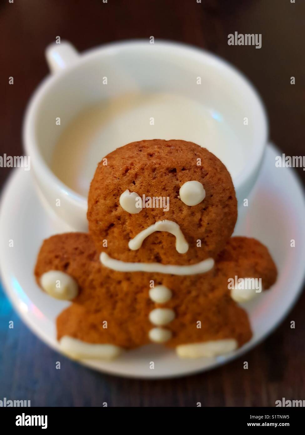 Une triste gingerbread cookie avant d'une tasse de chocolat blanc Banque D'Images