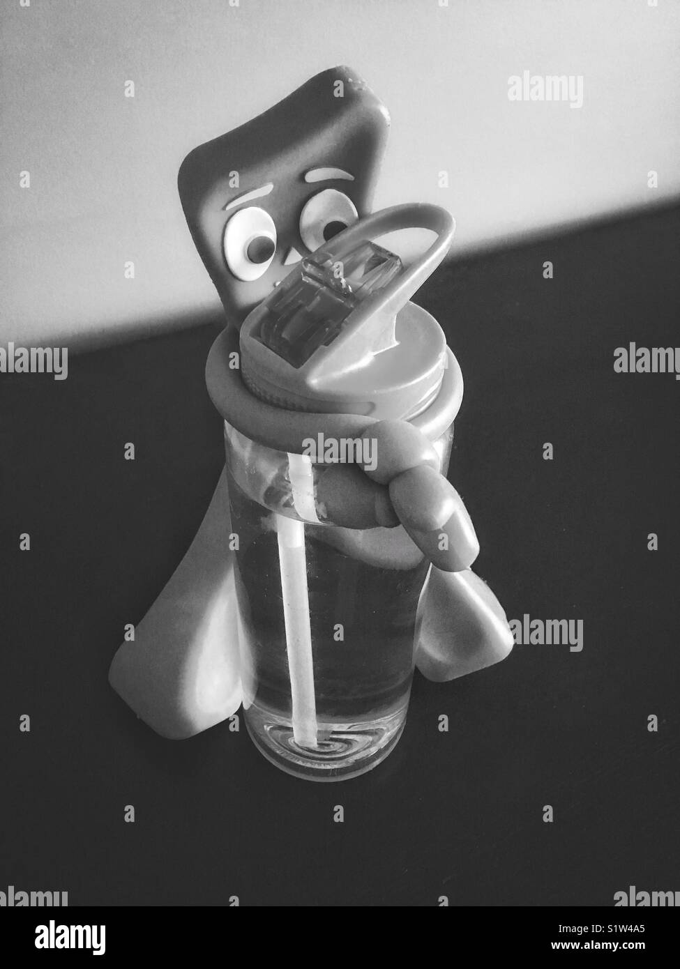 Jouet Gumby tenant une bouteille en plastique avec de l'eau, noir et blanc concept soif - Image de stock capturée avec un smartphone