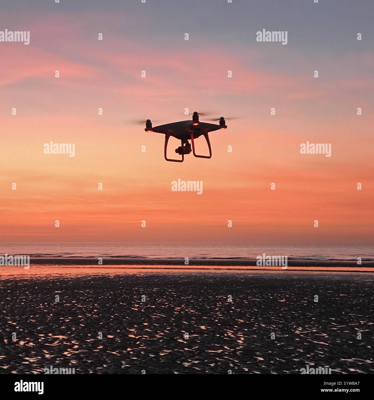 Une caméra drone voler contre un fond coloré coucher du soleil Banque D'Images