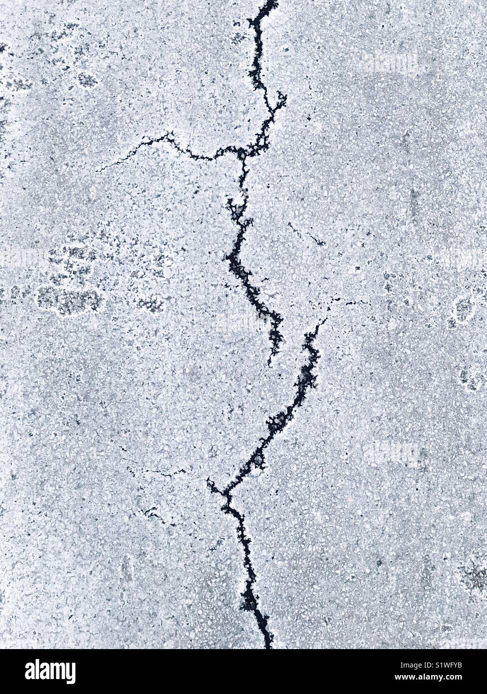 La surface de la route en hiver avec du sel et des fissures dans l'asphalte. - Image de stock capturée avec un smartphone