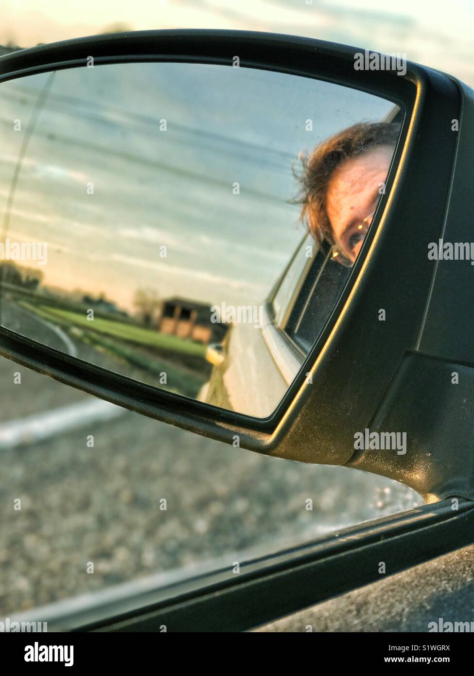 Visage d'un homme sur le côté de la voiture miroir Banque D'Images