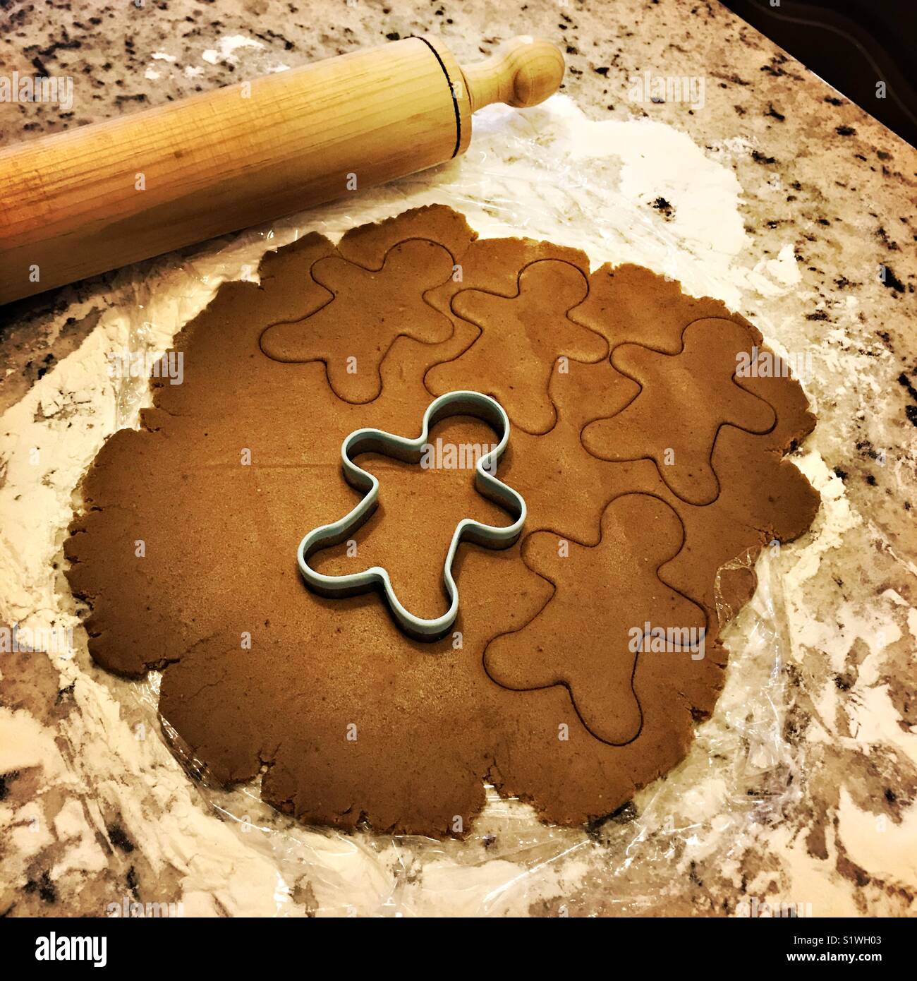 Gingerbread cookie dough est déployée sur un plan de travail en marbre avec un emporte-pièce d'épices dans la pâte et un rouleau à côté de la pâte. Banque D'Images
