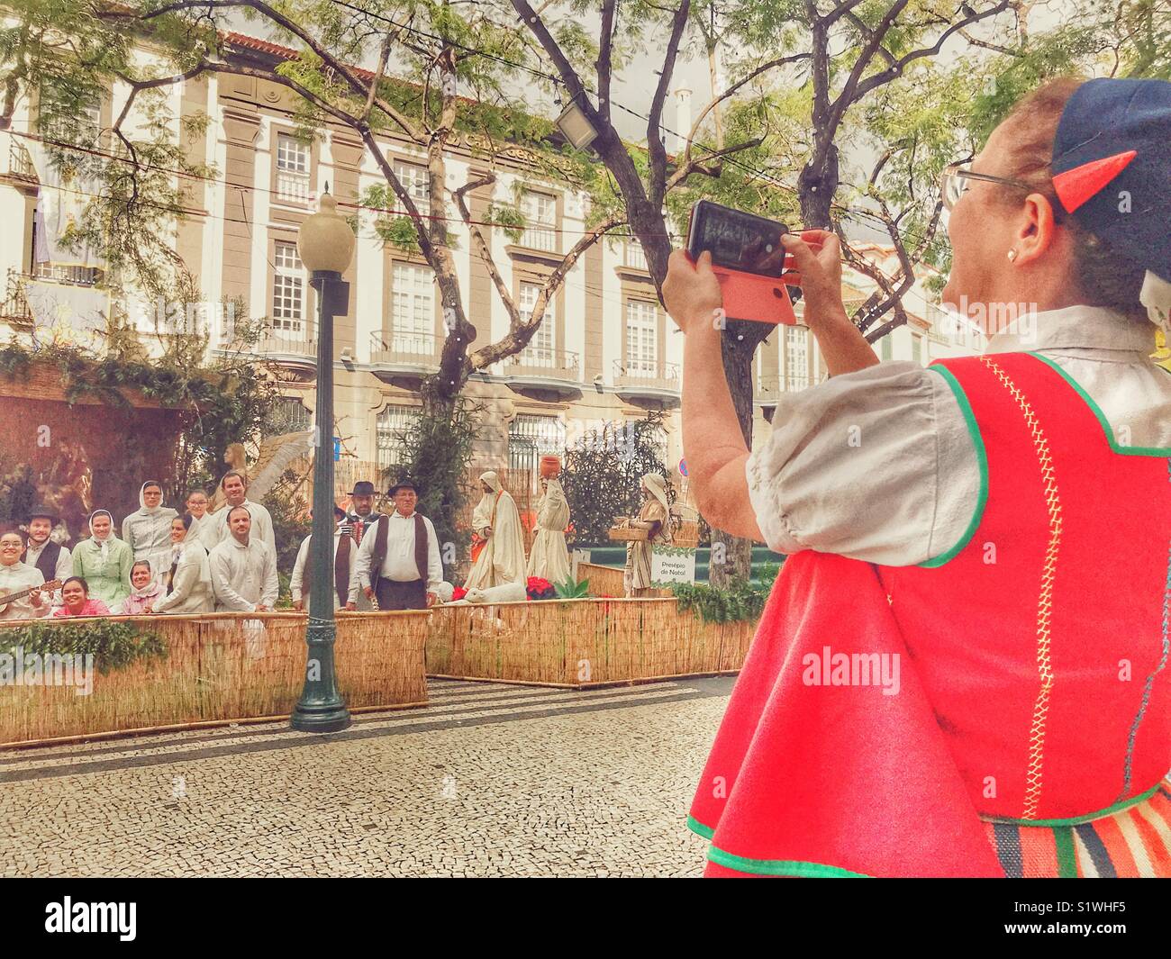 Femme madérienne à prendre des photos d'un groupe de danseurs et musiciens avec un téléphone-appareil photo. Funchal, Madeira, Portugal Banque D'Images