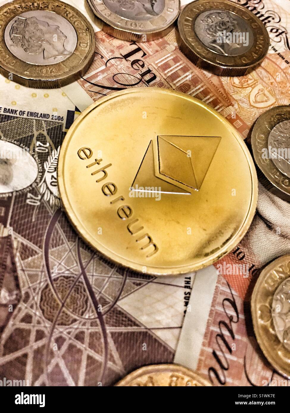 Une pièce d'Ethereum et pièces livre sterling britannique - Image de stock capturée avec un smartphone