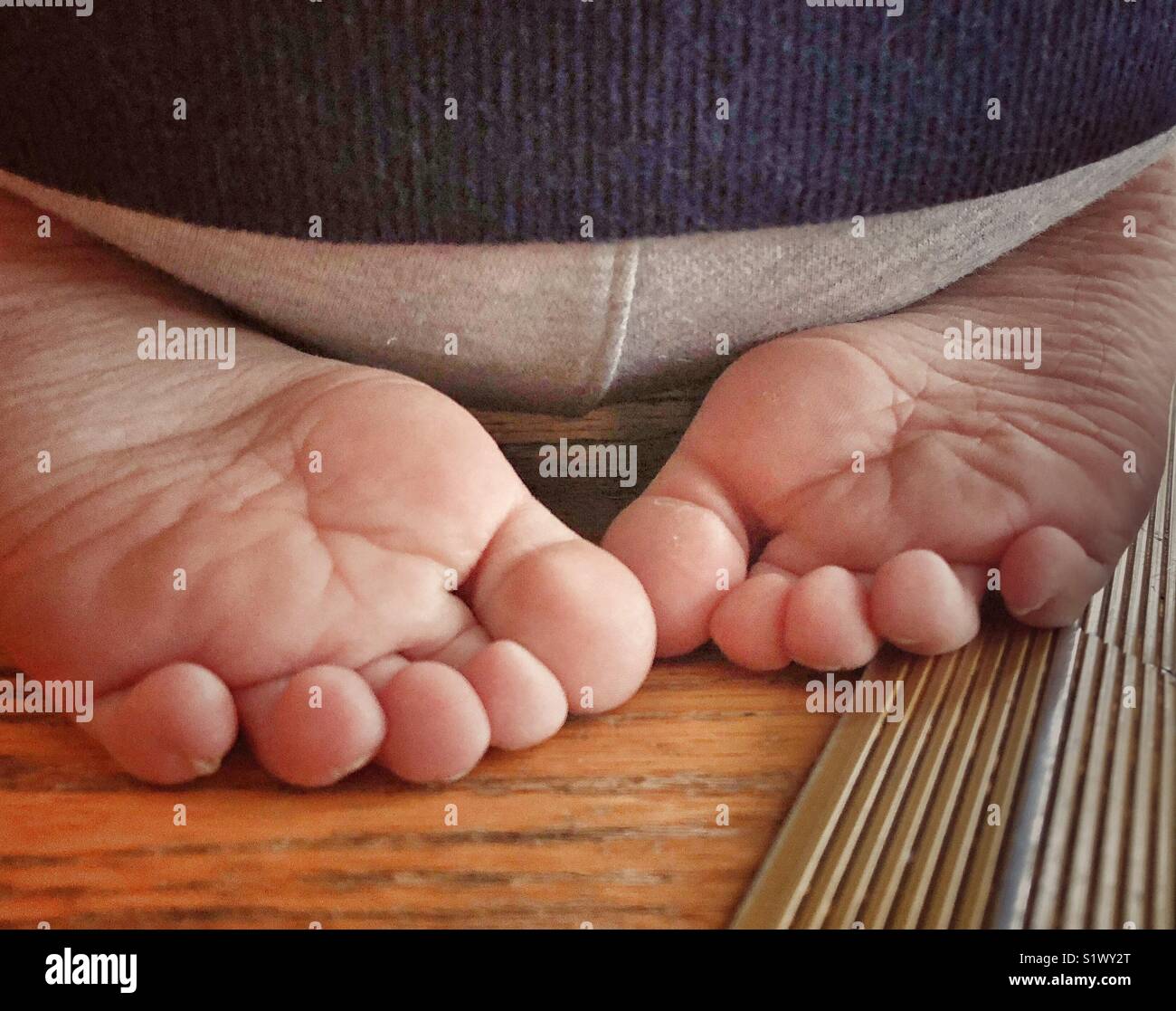 Libre de tout-petit pieds repliés sous derrière tout en étant assis sur le plancher - Image de stock capturée avec un smartphone