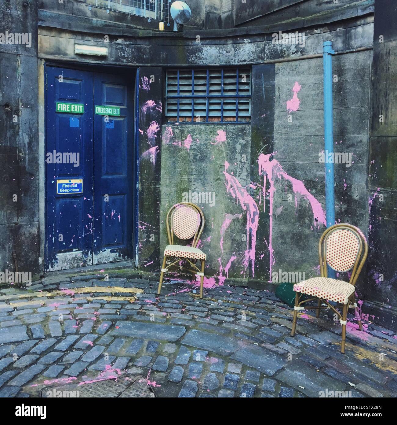 Peinture rose éclaboussés à travers un mur, avec des chaises abandonnées, off the Street, Édimbourg Banque D'Images
