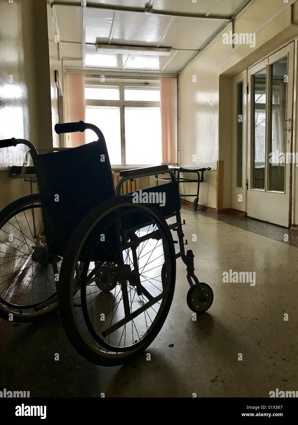 L'ancien hôpital de l'intérieur. Mobilité fauteuil roulant pour le  transport de patients ne marche pas. Dans le rétro-éclairage spectaculaire  de la fenêtre de l'hôpital Photo Stock - Alamy