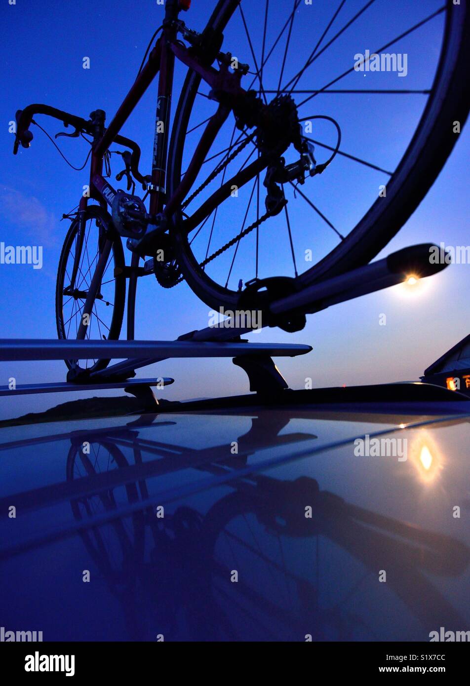 Un vélo sur le toit d'une voiture en silhouette Banque D'Images