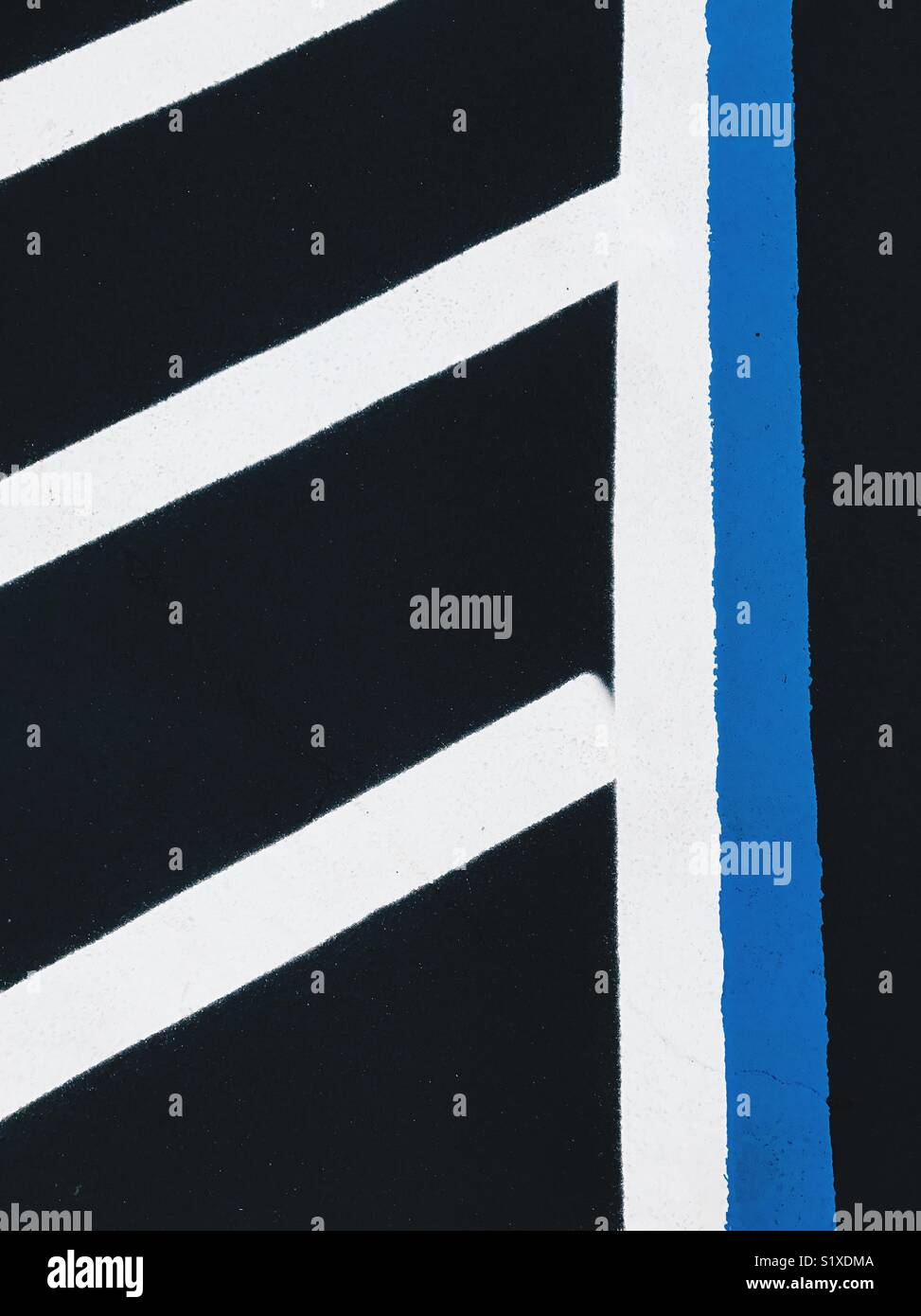 Bold peint en blanc et bleu sur les lignes d'asphalte noir dans un parking. Banque D'Images