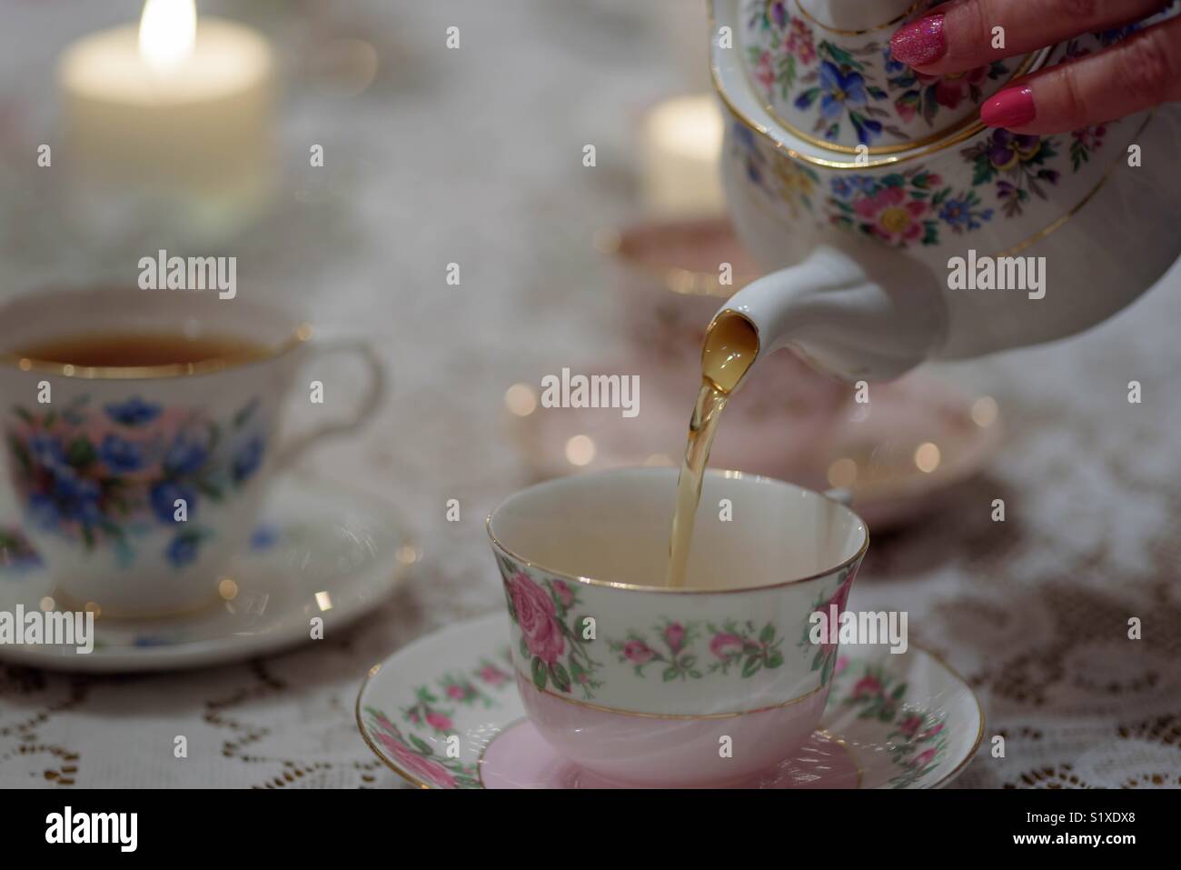 Femme avec des ongles rose thé verser d'une théière vintage china Banque D'Images