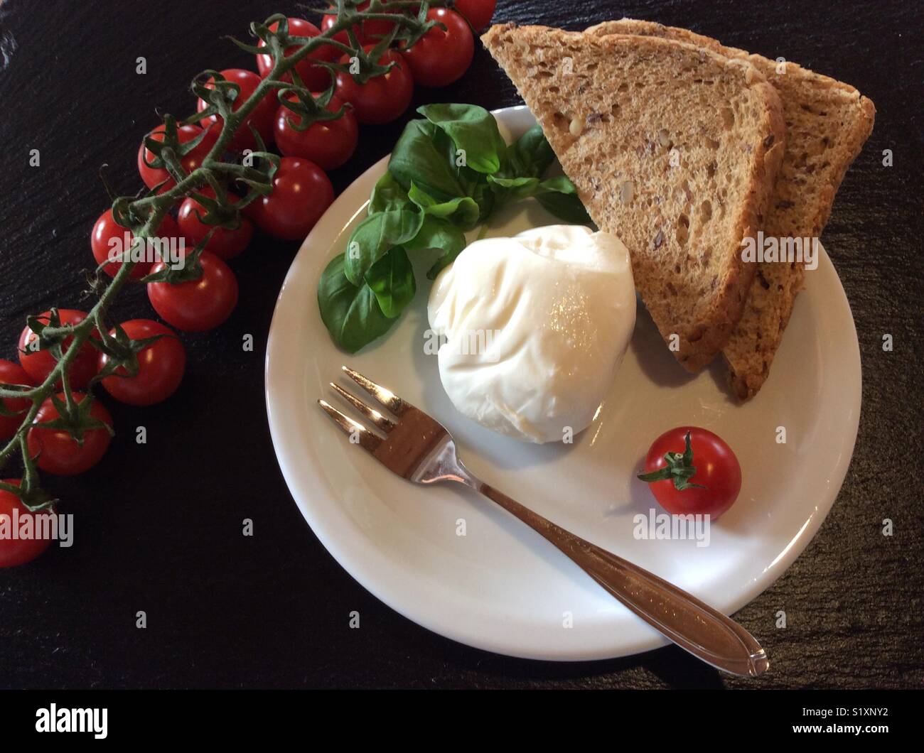 Boule de fromage mozzarella unique, pain de grains entiers, tomates, basilic et fourche food Banque D'Images