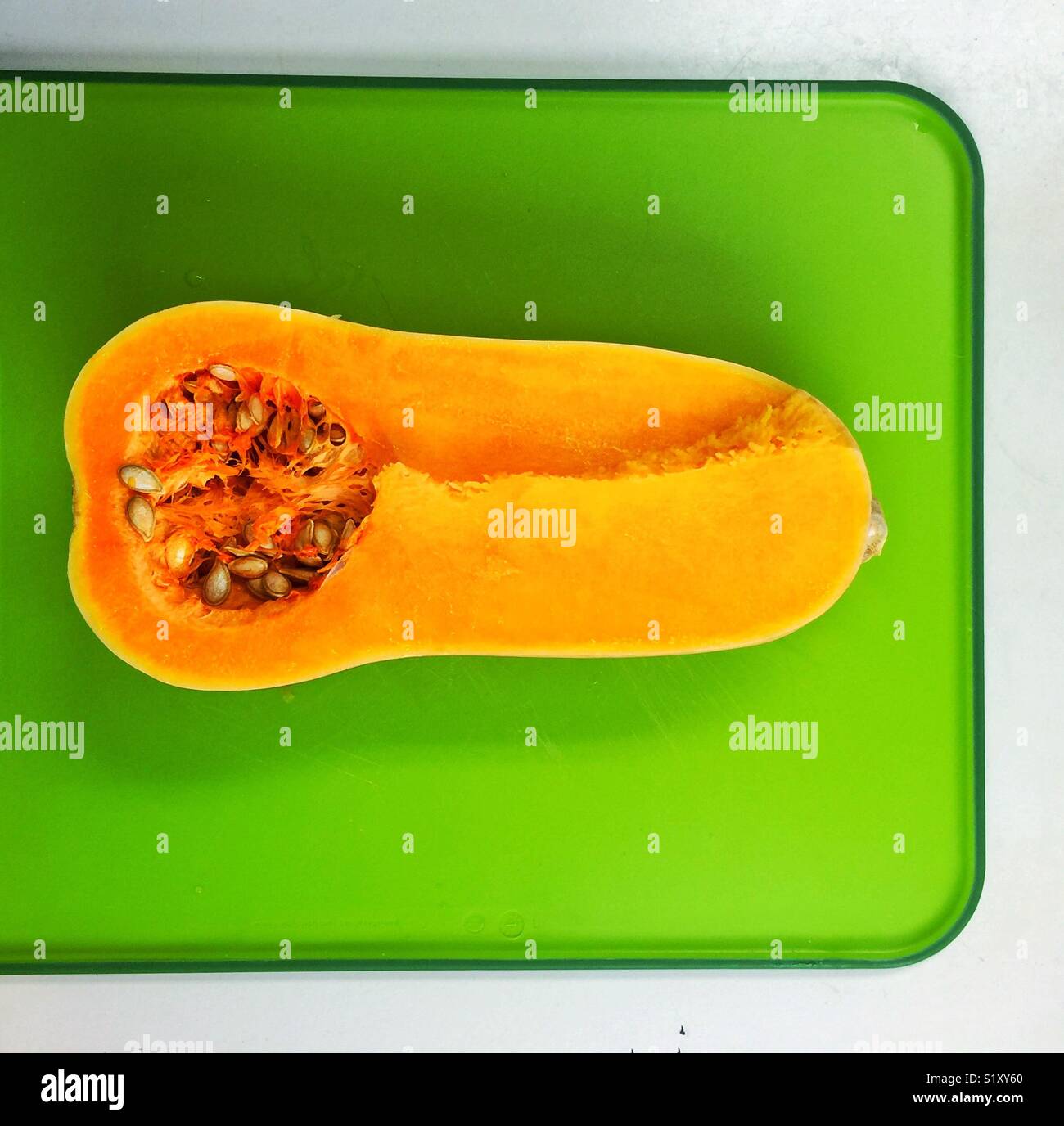 Courge Butternut coupée en deux sur une planche à découper verte Banque D'Images