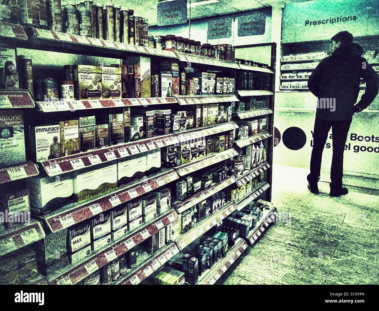 Boots the Chemist, intérieur, bien approvisionné avec une variété de médicaments en vente libre et d'une personne debout au comptoir pour recueillir une ordonnance Banque D'Images