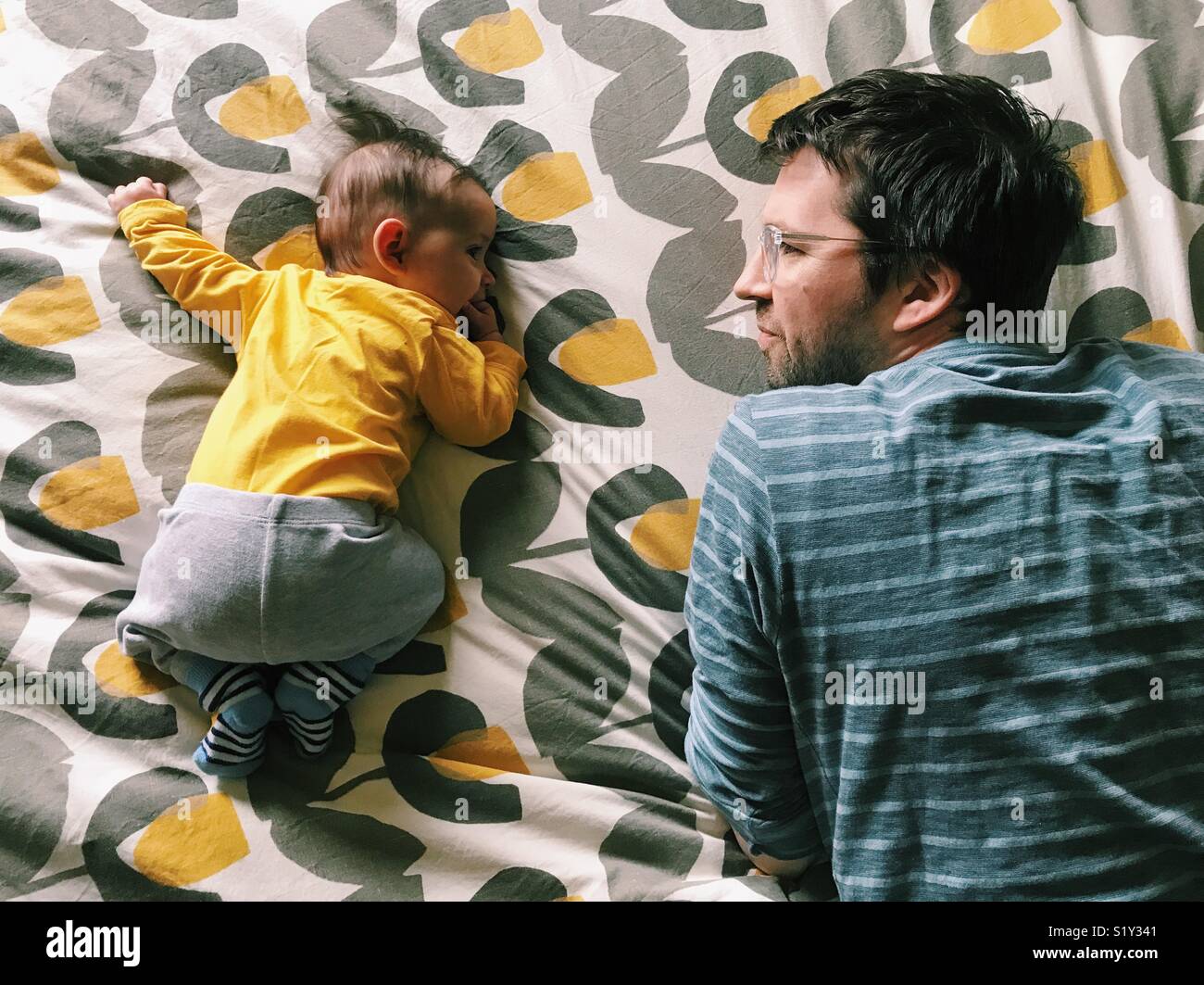 À plat ventre pour une petite fille avec son père en regardant à côté d'elle. - Image de stock capturée avec un smartphone
