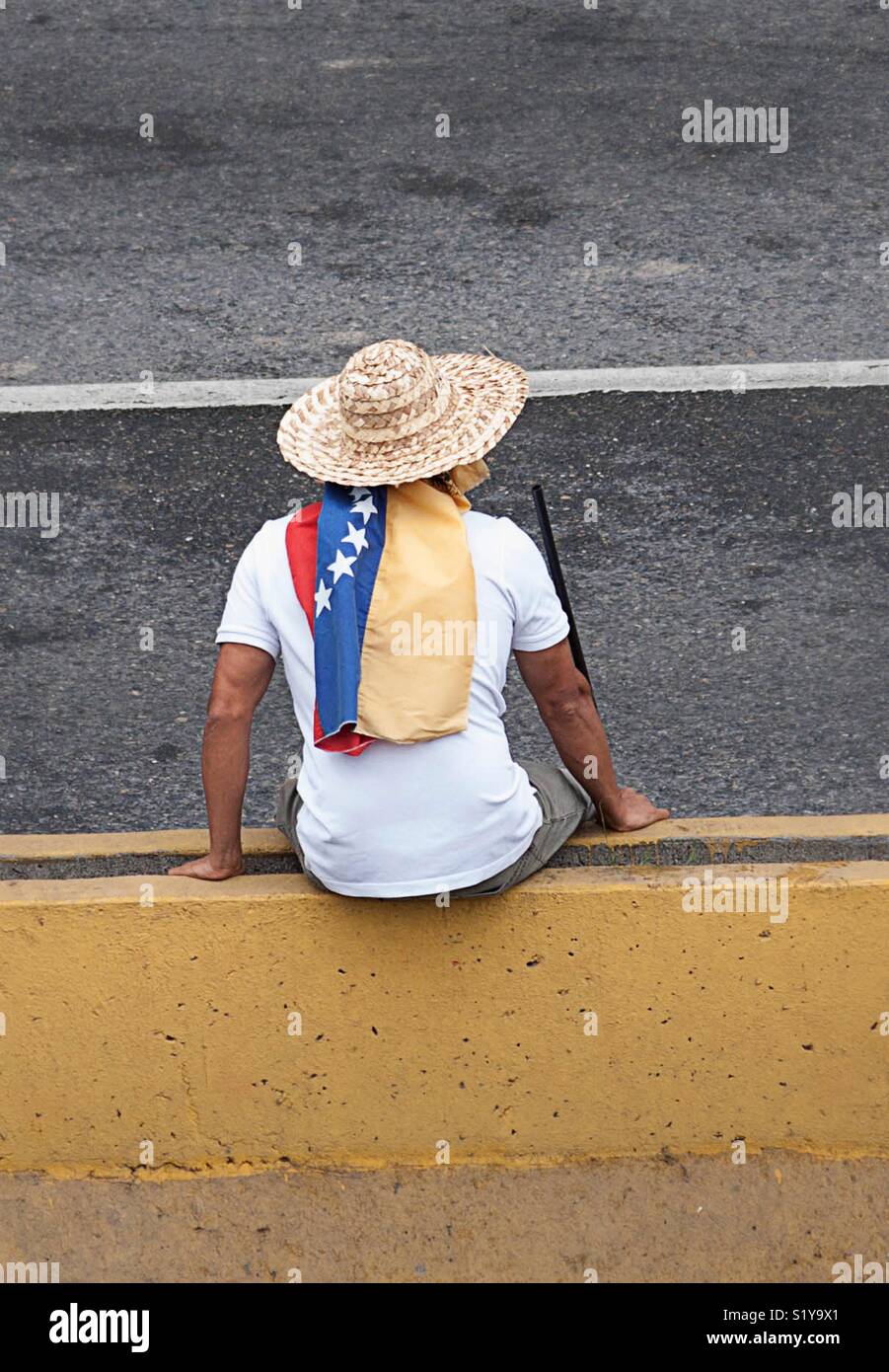 Un homme avec un chapeau assis sur la rue au cours d'une protestation contre le président Nicolas Maduro - Image de stock capturée avec un smartphone