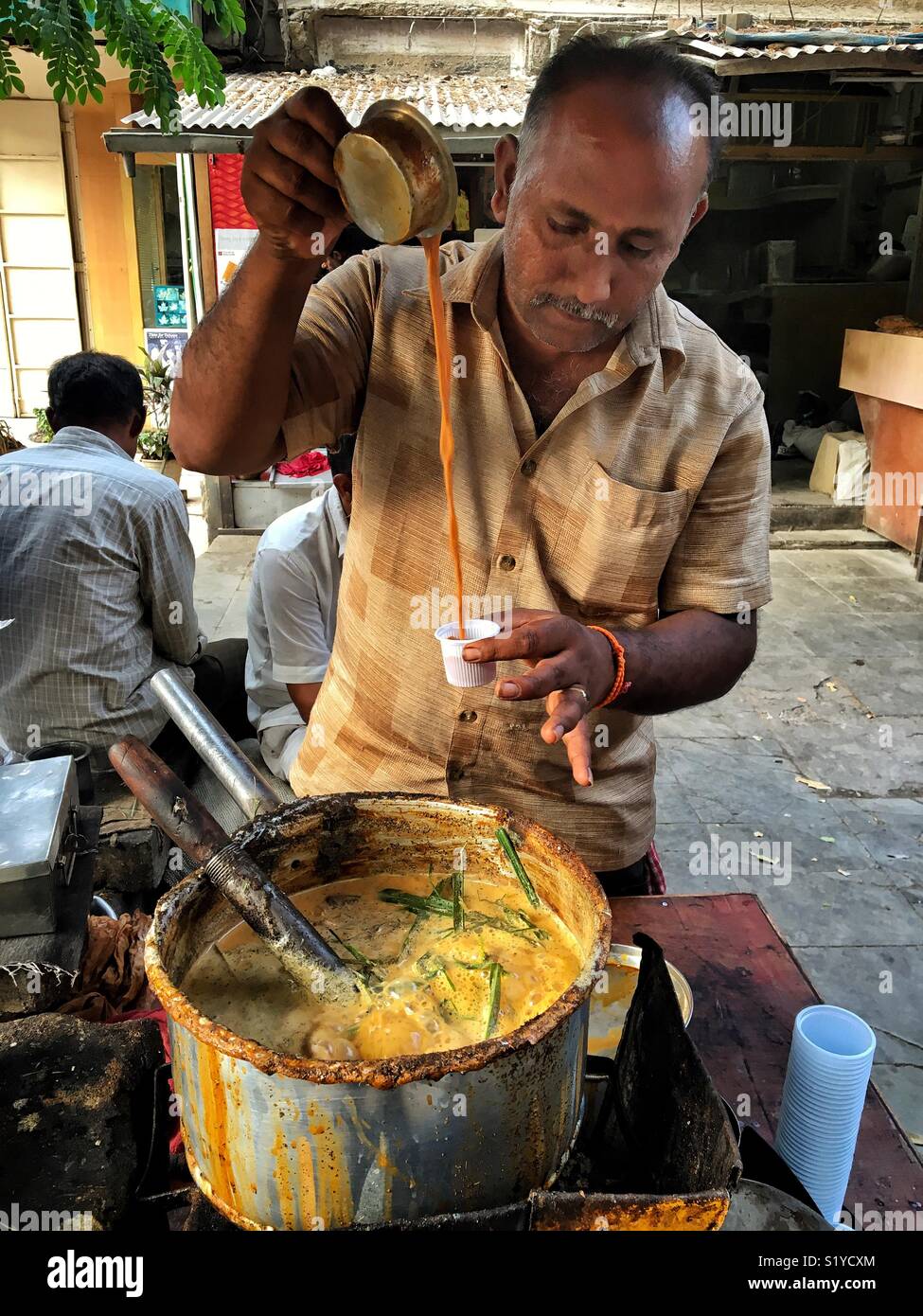 Un plateau en bordure de la caler à Mumbai. Incroyable qui fait le thé vert en poudre de thé, lait, sucre et à la saveur ajoute-t-il beaucoup de feuilles de citronnelle et gingembre fraîchement broyée. - Image de stock capturée avec un smartphone